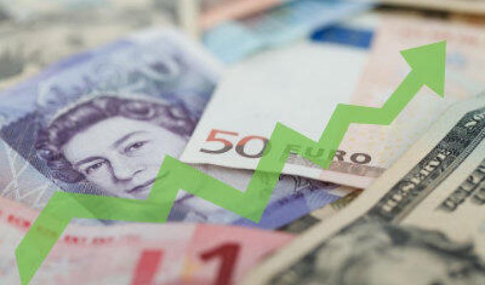 banknoty różnych walut ze strzałką pnącą się w górę symbolizującą wzrosty lub zyski